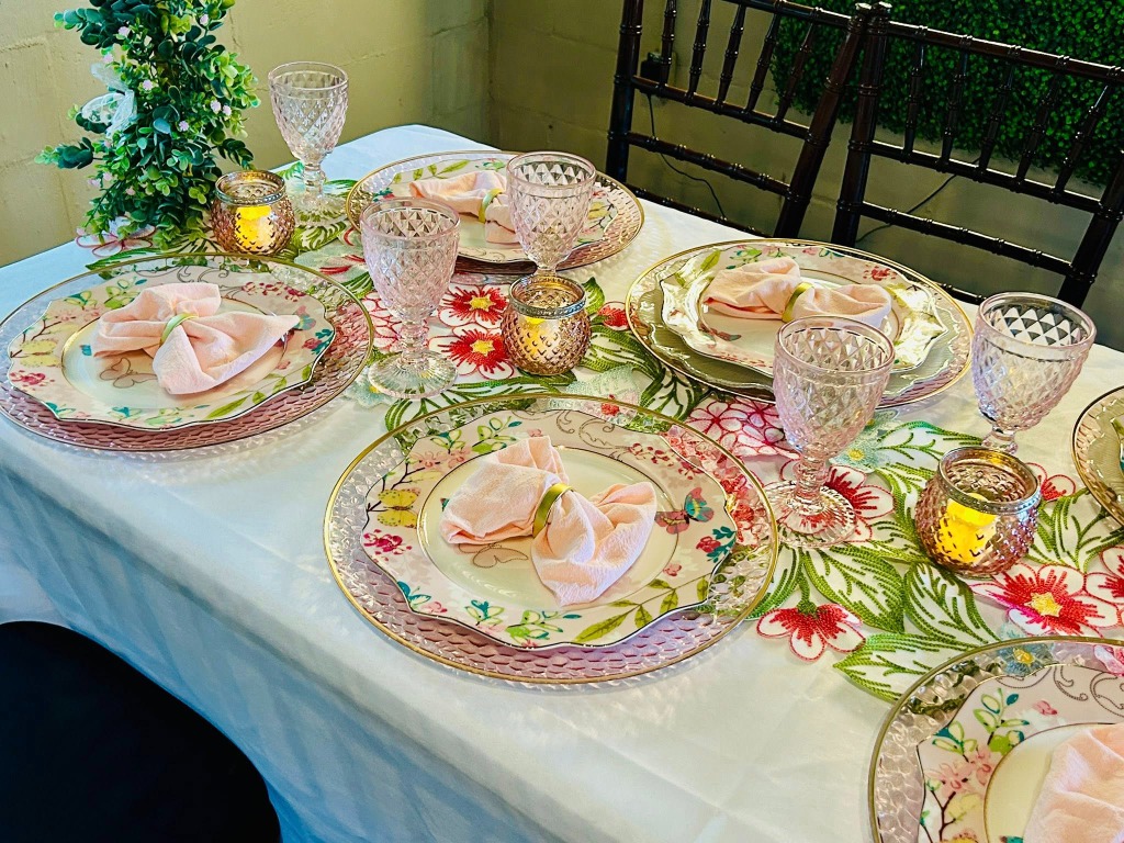 Place setting with floral plates, pink napkins, and crystal glassware
