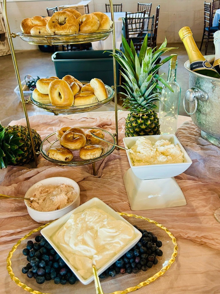 Another angle of the food display with fresh fruit and bagels