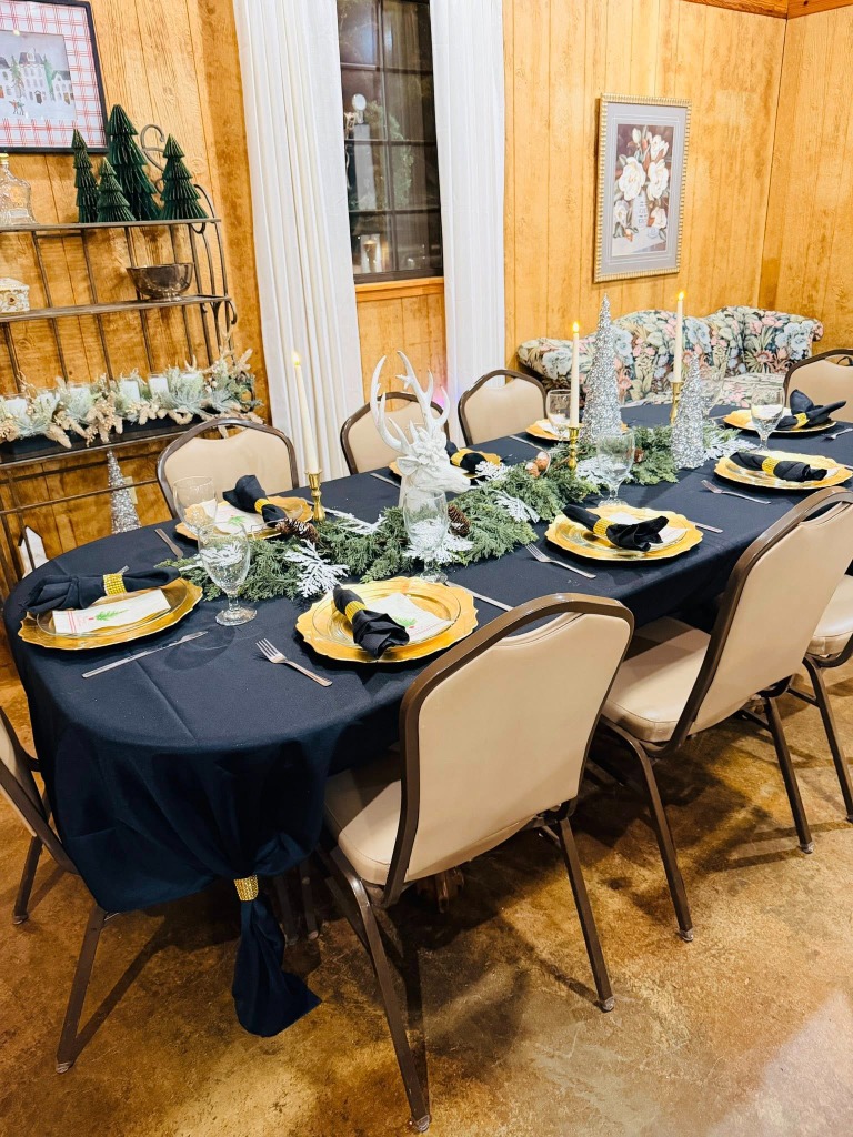 Elegant dark tablecloth setting with gold chargers and Christmas tree decor