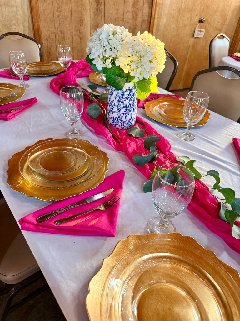 Close up of place setting with gold charger and pink napkin