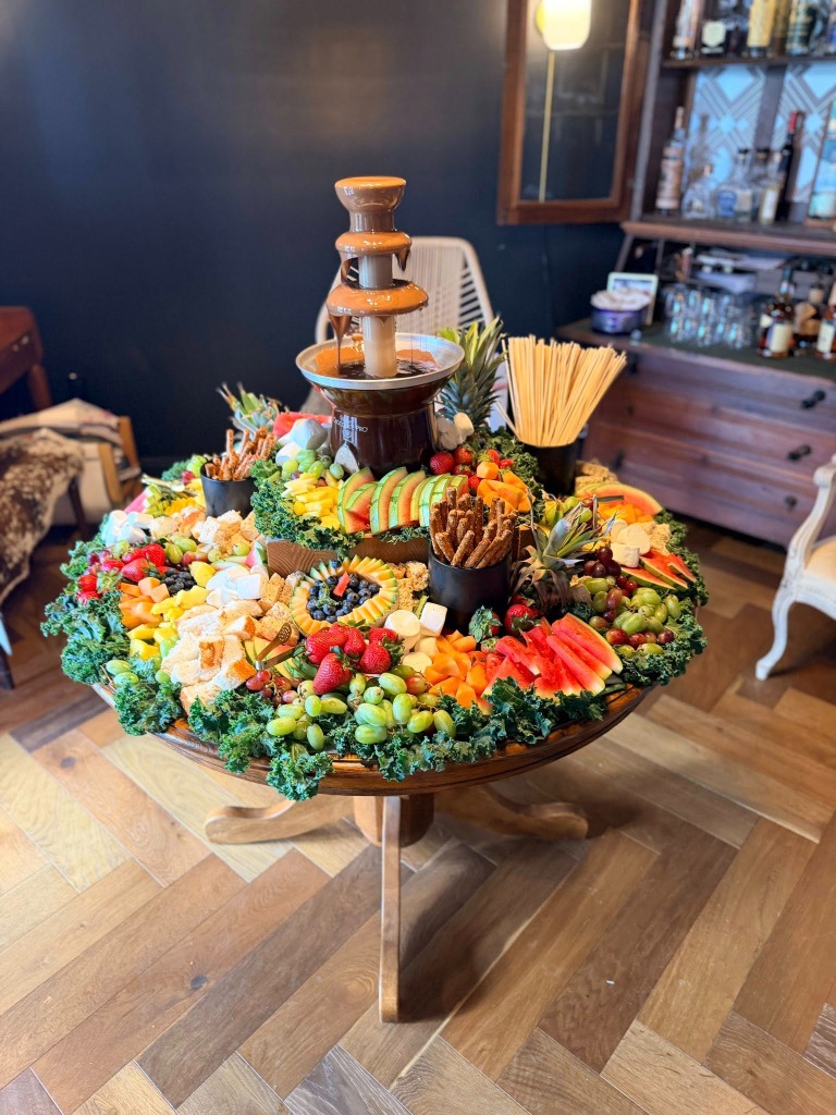 Large charcuterie and fruit display with a flowing chocolate fountain
