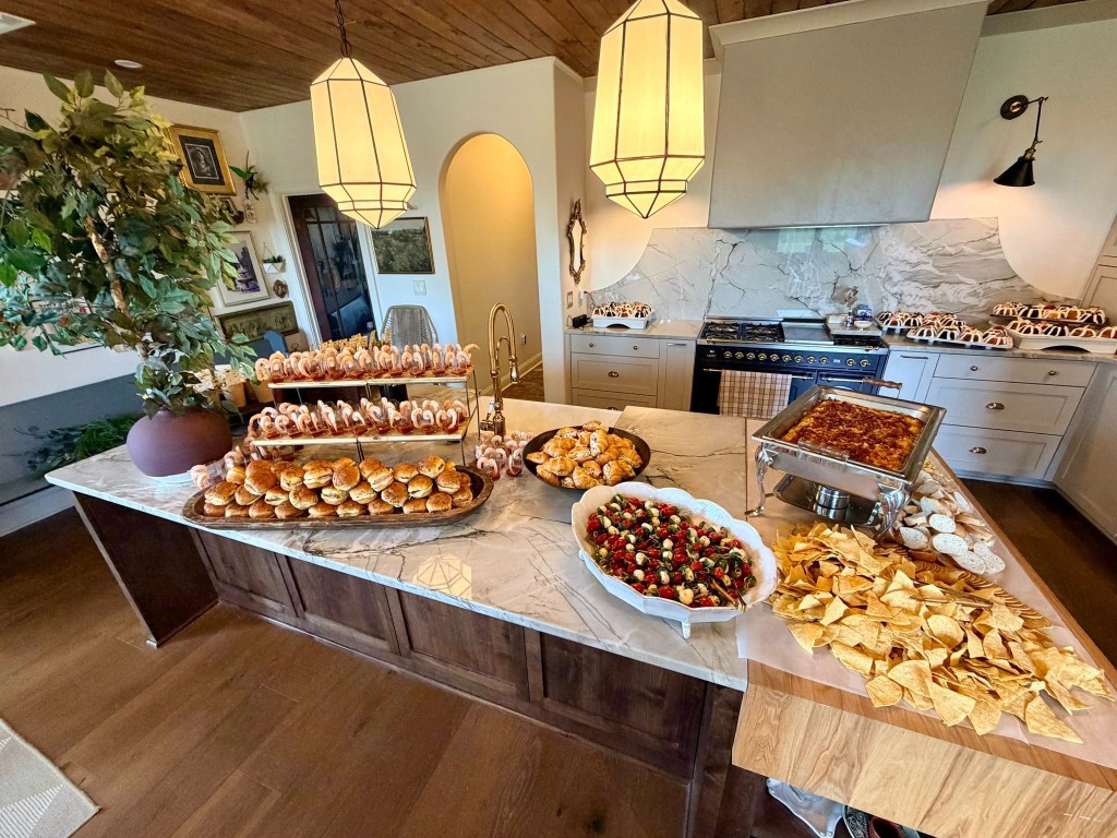 Kitchen island spread with snacks, sandwiches, and dips